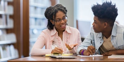 A court appointed special advocate is meeting with a boy in a library.